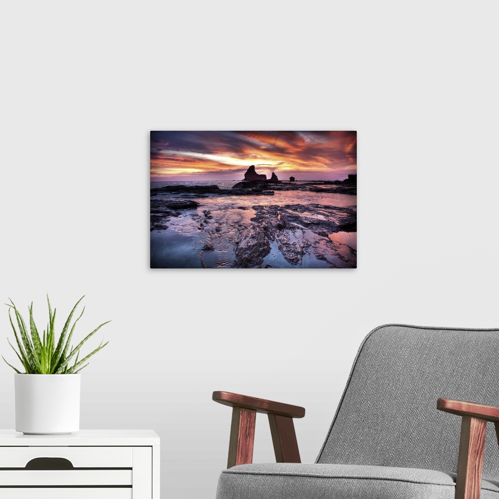 A modern room featuring A photograph of a dramatic coastal sunset scene.