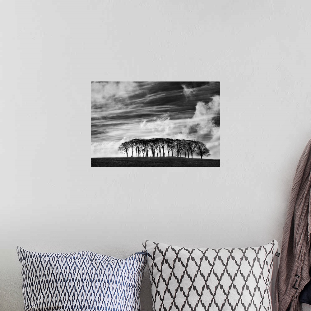 A bohemian room featuring A black and white photograph using high contrast to highlight a sky filled with clouds and a smal...