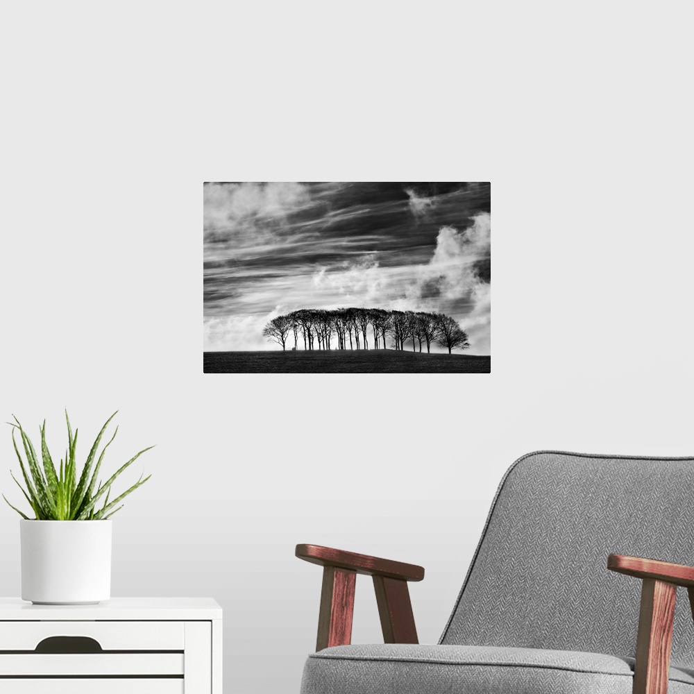 A modern room featuring A black and white photograph using high contrast to highlight a sky filled with clouds and a smal...