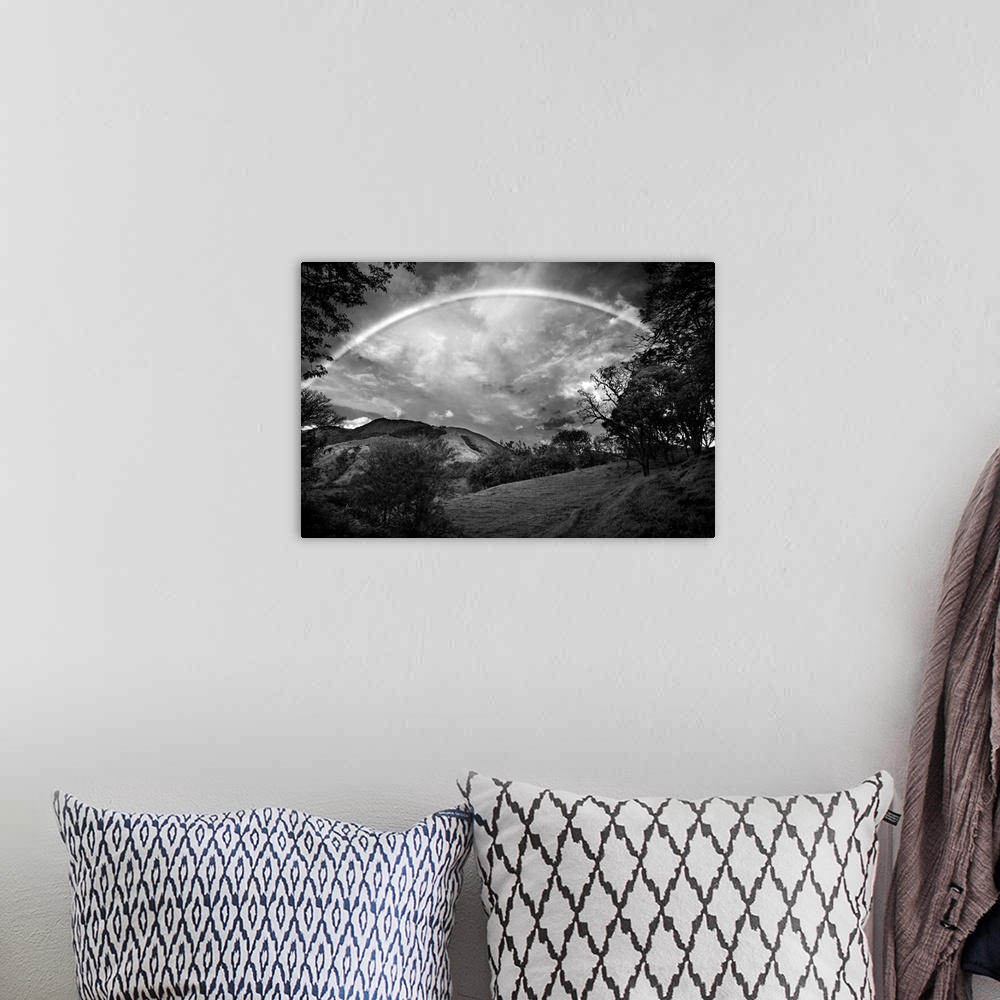 A bohemian room featuring Black and white photograph of a wilderness landscape with a large rainbow in the sky.