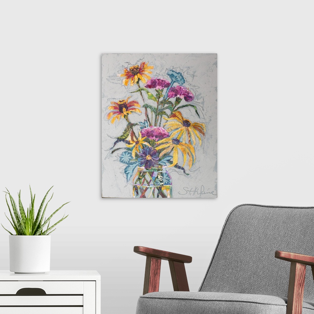 A modern room featuring Yellow, pink, blue, purple, and orange flowers in a glass jar on neutral gray/blue background. Mi...