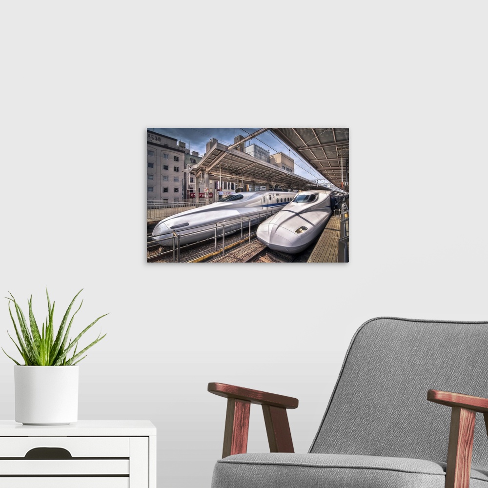 A modern room featuring HDR photograph of two bullet trains stopped at a station in Japan.