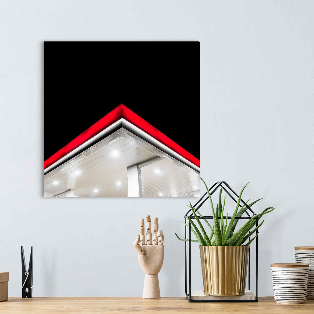 A bohemian room featuring The bright red edge of a gas station overhang at night.