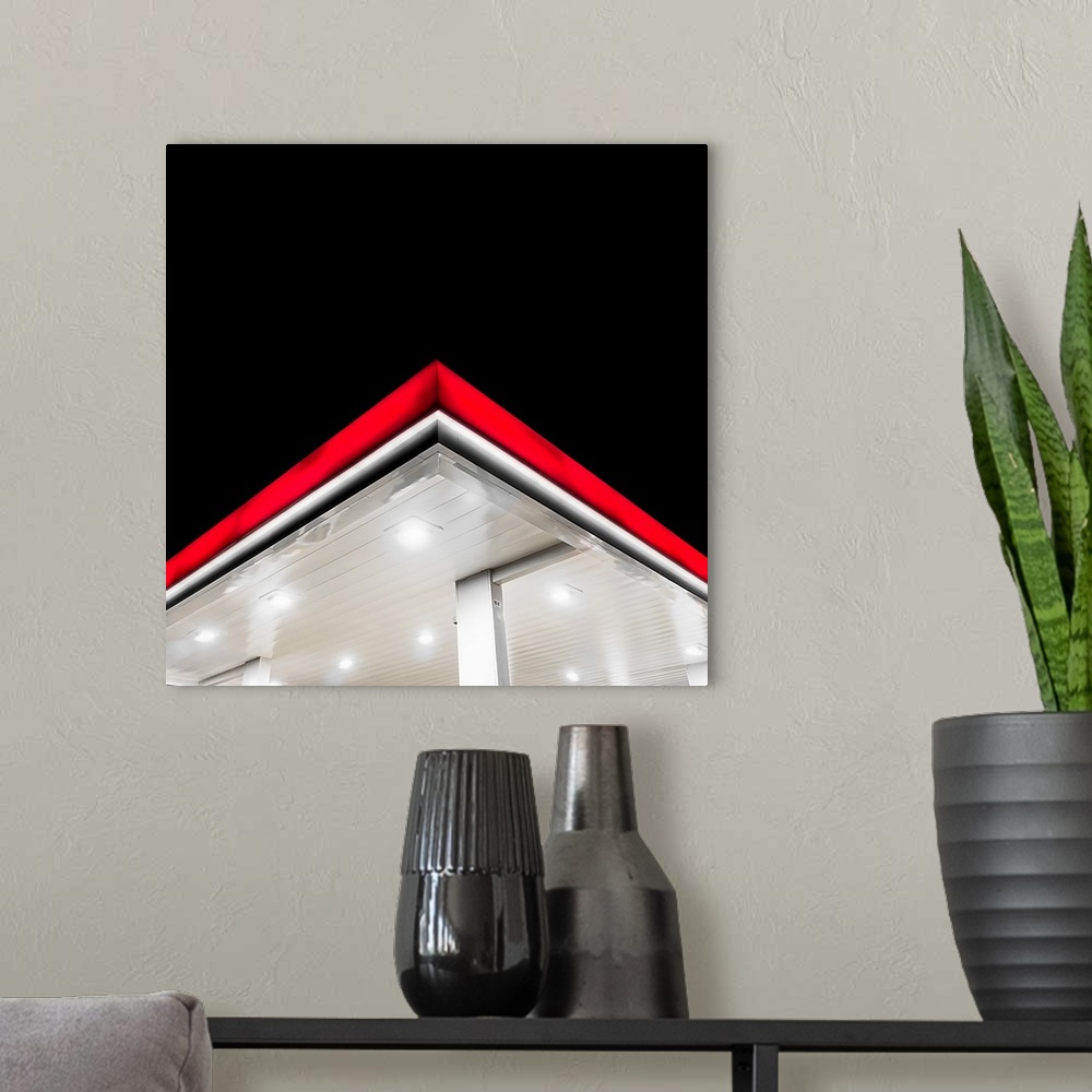 A modern room featuring The bright red edge of a gas station overhang at night.