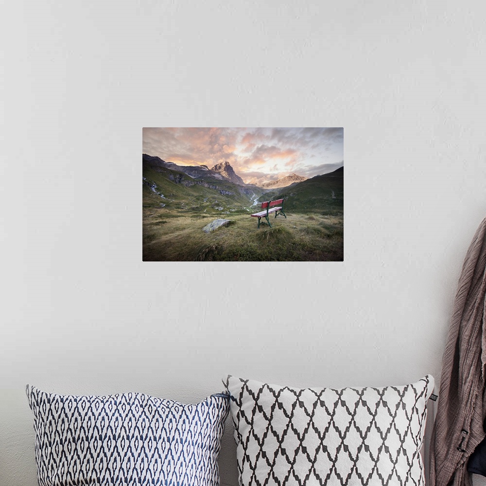 A bohemian room featuring Dramatic clouds over a mountain valley with a bench.