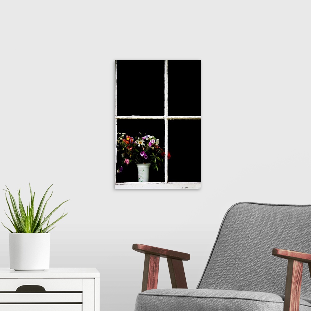 A modern room featuring An old white window frame with a white vase filled with a jumble of cottage garden flowers.