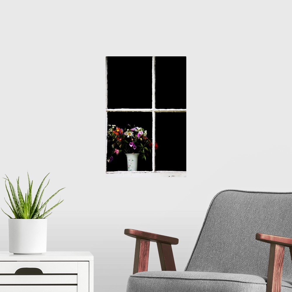 A modern room featuring An old white window frame with a white vase filled with a jumble of cottage garden flowers.