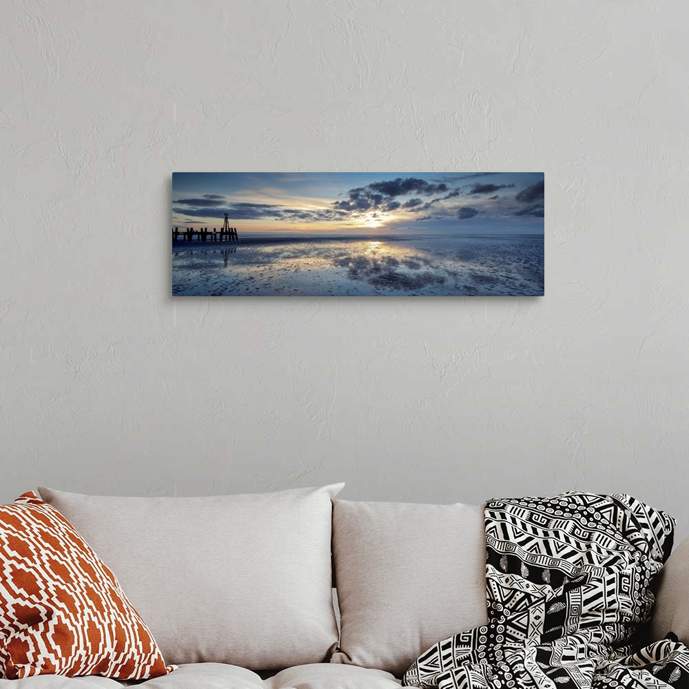A bohemian room featuring A panoramic image of a tranquil golden blue dawn with fluffy clouds over reflecting wet sand with...
