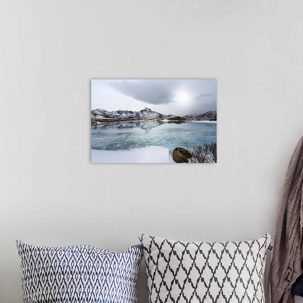 A bohemian room featuring A photograph of a mountain range seen reflected in a lake below it.