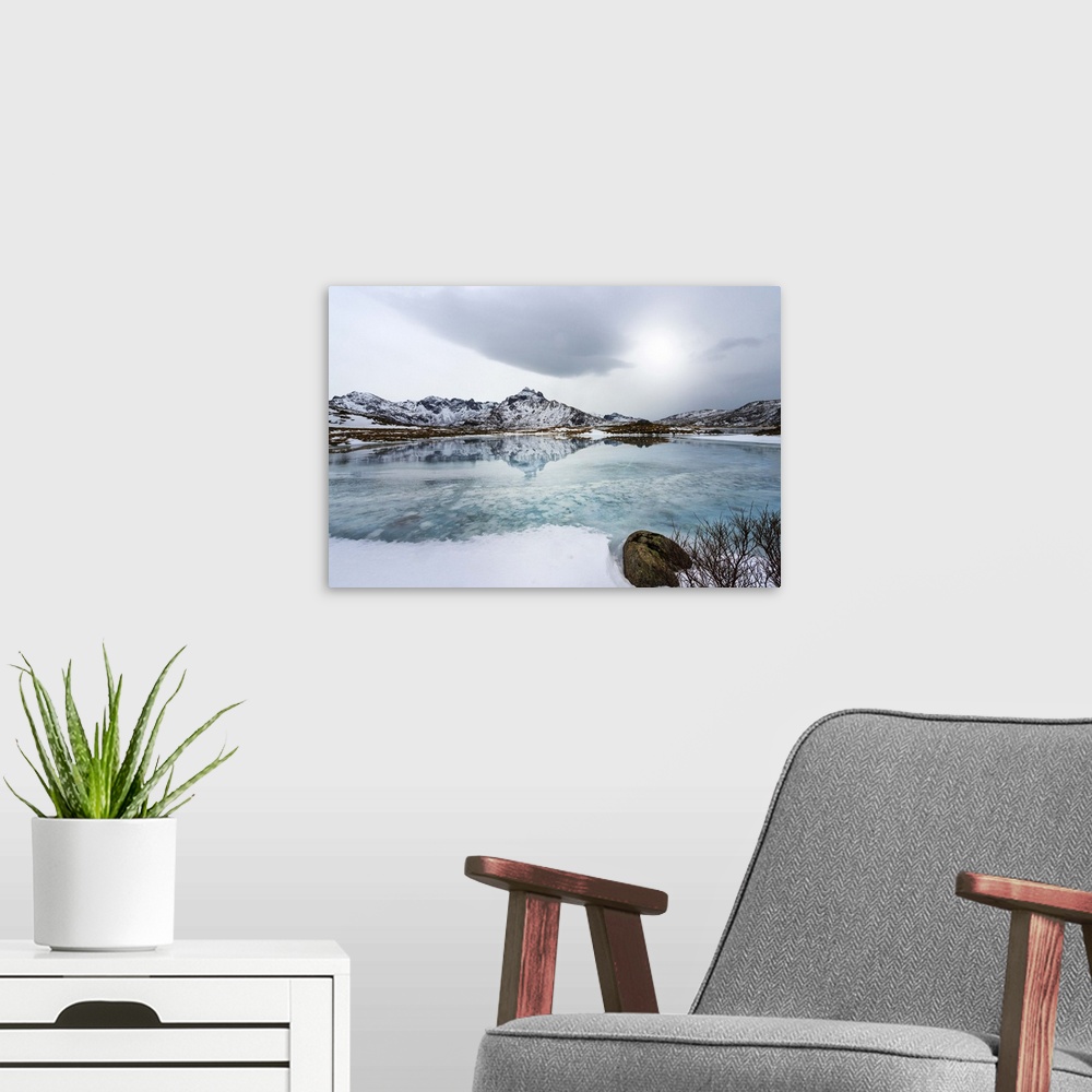 A modern room featuring A photograph of a mountain range seen reflected in a lake below it.