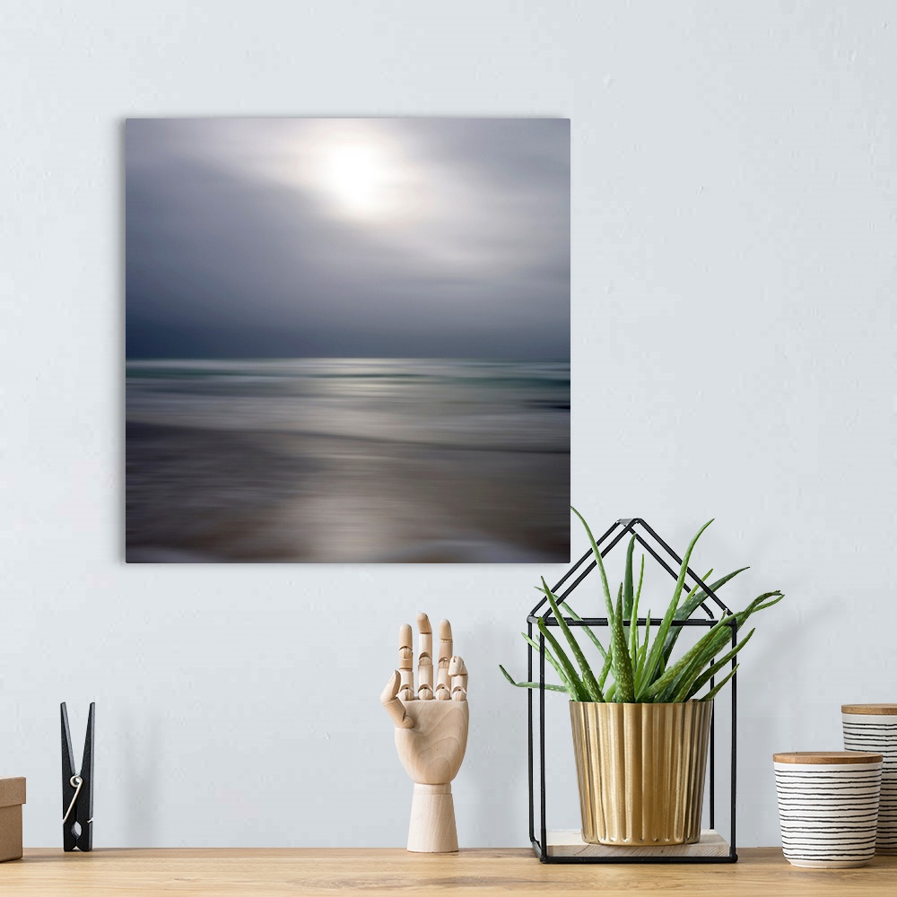 A bohemian room featuring Giant photograph displays an ocean gently making its way to a sandy shore while underneath a clou...