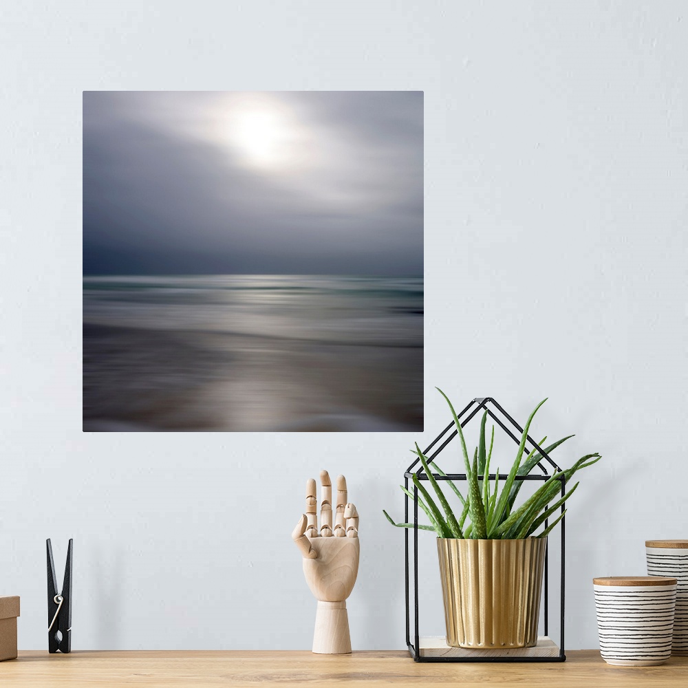 A bohemian room featuring Giant photograph displays an ocean gently making its way to a sandy shore while underneath a clou...