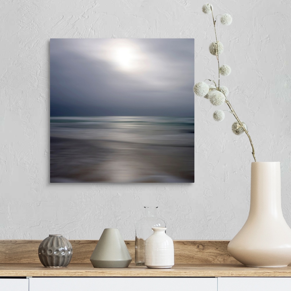 A farmhouse room featuring Giant photograph displays an ocean gently making its way to a sandy shore while underneath a clou...