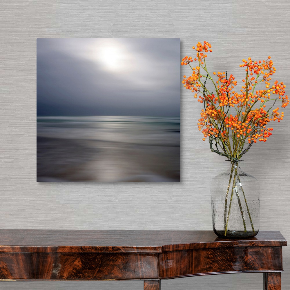 A traditional room featuring Giant photograph displays an ocean gently making its way to a sandy shore while underneath a clou...