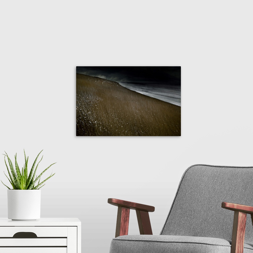 A modern room featuring Abstract photograph of a beach landscape with dark ocean waves crashing on a dark sandy beach wit...