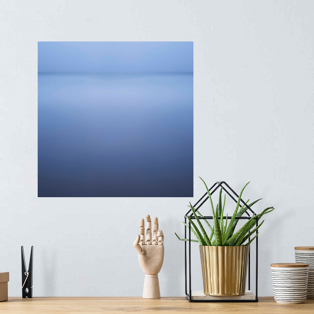 A bohemian room featuring Abstract artwork that has lighter shades of blue at the top of the print that becomes darker as y...