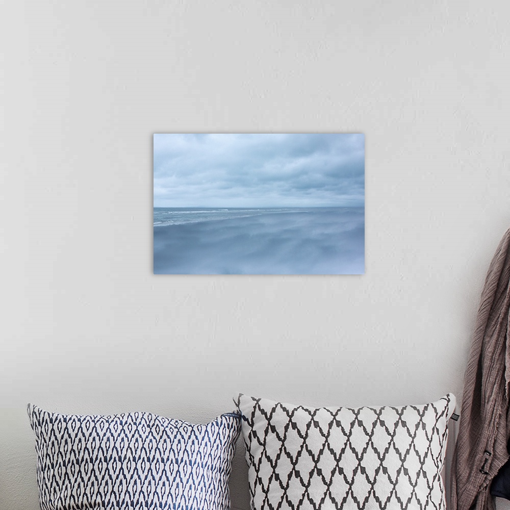 A bohemian room featuring Dense clouds over the ocean before a storm, in pale blue light.
