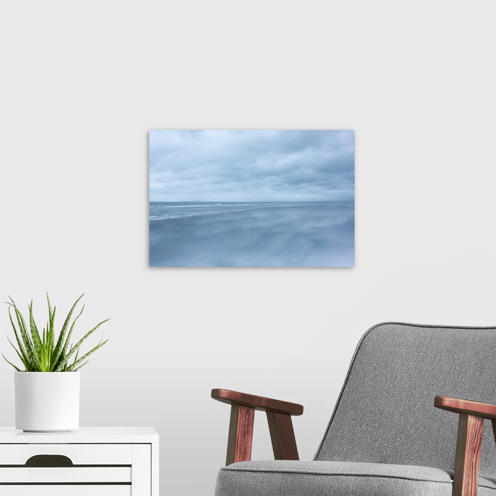 A modern room featuring Dense clouds over the ocean before a storm, in pale blue light.