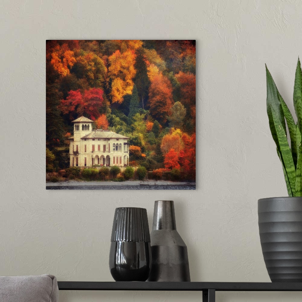 A modern room featuring This is a landscape photograph on square shaped wall docor that shows a lake side villa surrounde...