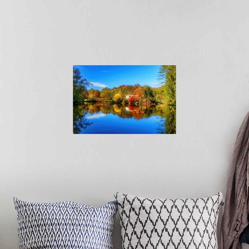 A bohemian room featuring Colorful trees in the fall and a deep blue sky reflected in the calm waters of a lake.