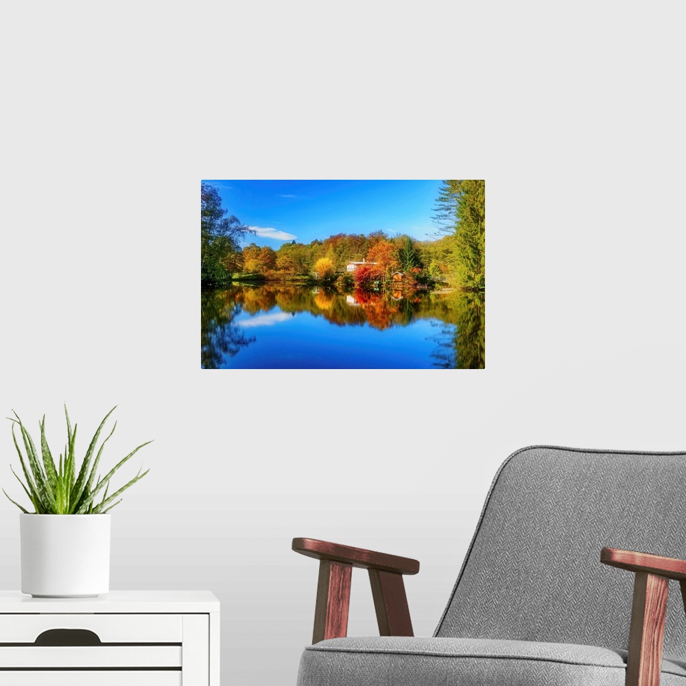 A modern room featuring Colorful trees in the fall and a deep blue sky reflected in the calm waters of a lake.