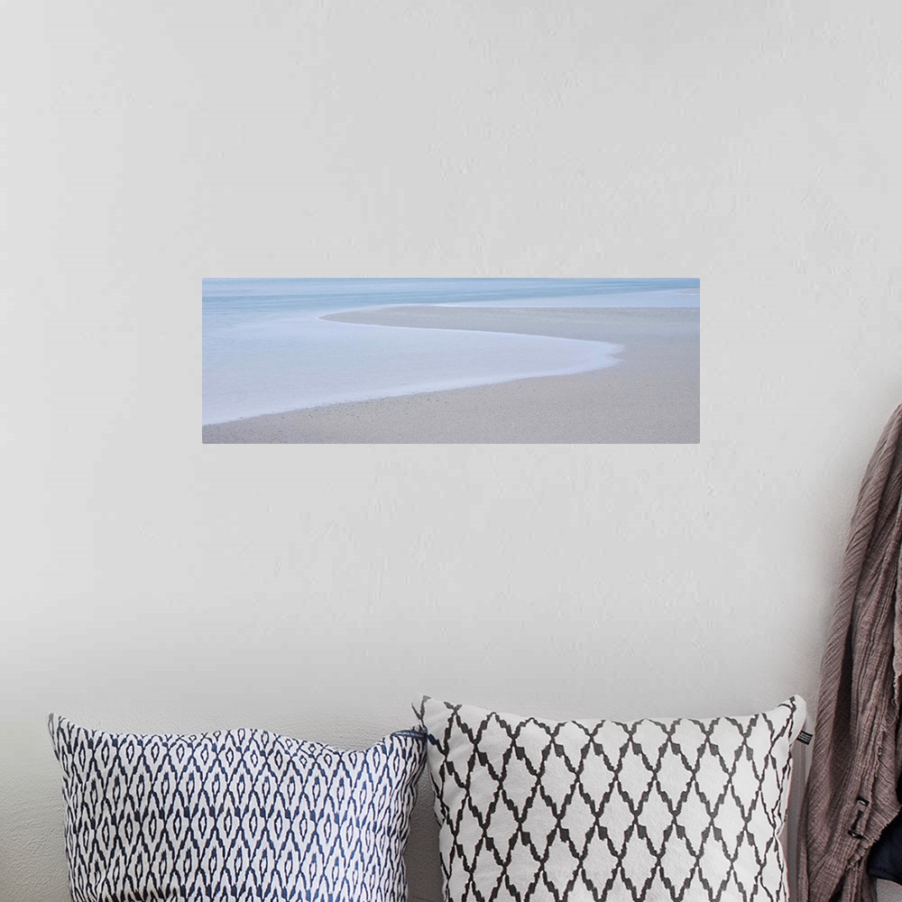 A bohemian room featuring A photograph of a long beach on a hazy day.