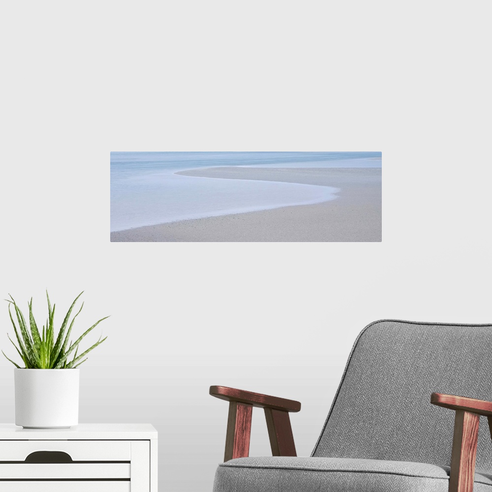 A modern room featuring A photograph of a long beach on a hazy day.