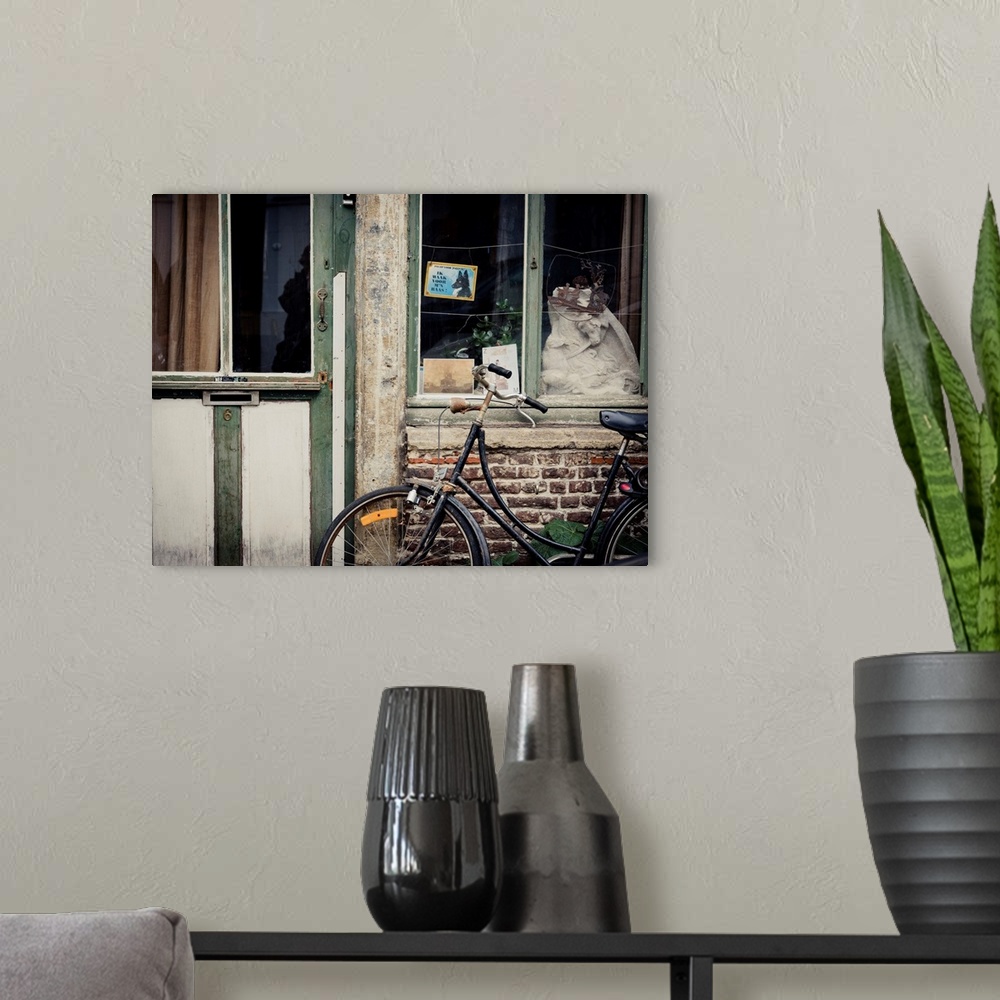 A modern room featuring A photo of an aged building with a bicycle and a beware of dog sign in dutch out front.