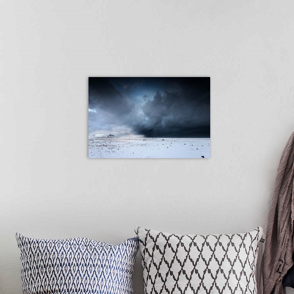 A bohemian room featuring A photograph of a snowscape under a sky filled with dark rolling clouds.