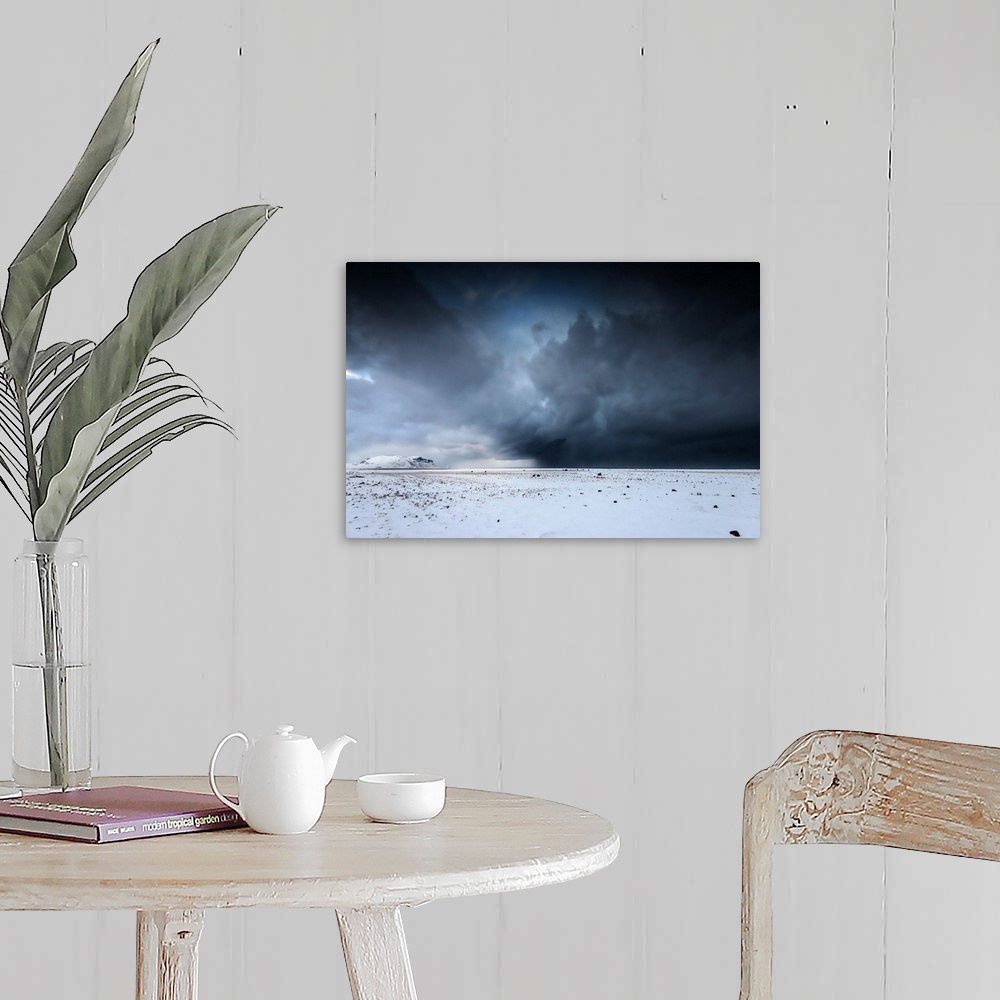 A farmhouse room featuring A photograph of a snowscape under a sky filled with dark rolling clouds.