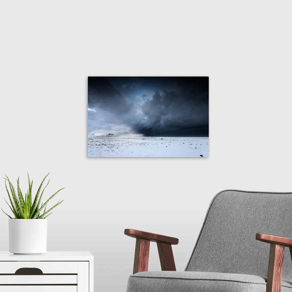 A modern room featuring A photograph of a snowscape under a sky filled with dark rolling clouds.