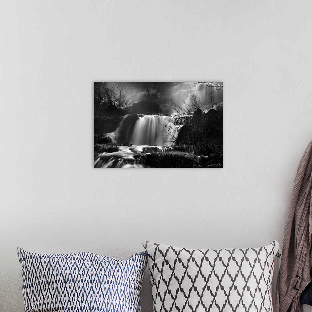 A bohemian room featuring This black and white photograph is taken of several small waterfalls that are surrounded by bare ...