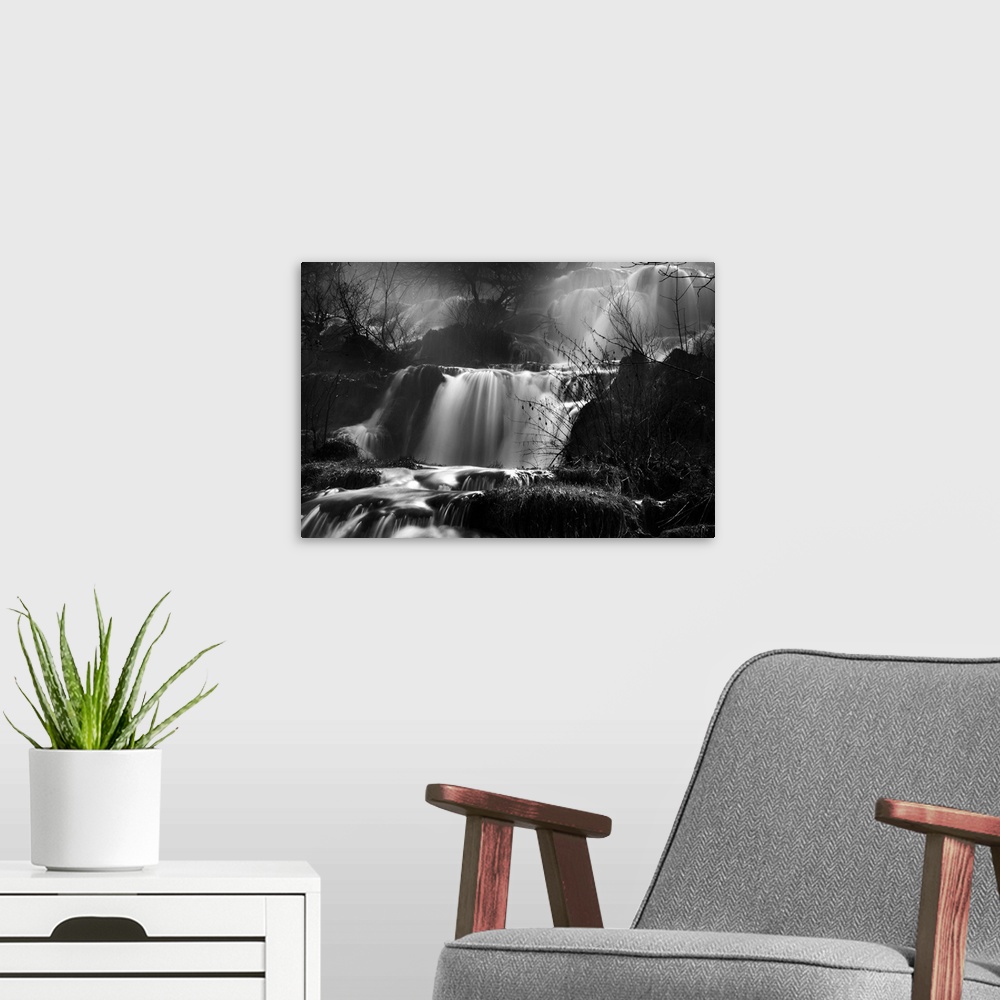 A modern room featuring This black and white photograph is taken of several small waterfalls that are surrounded by bare ...