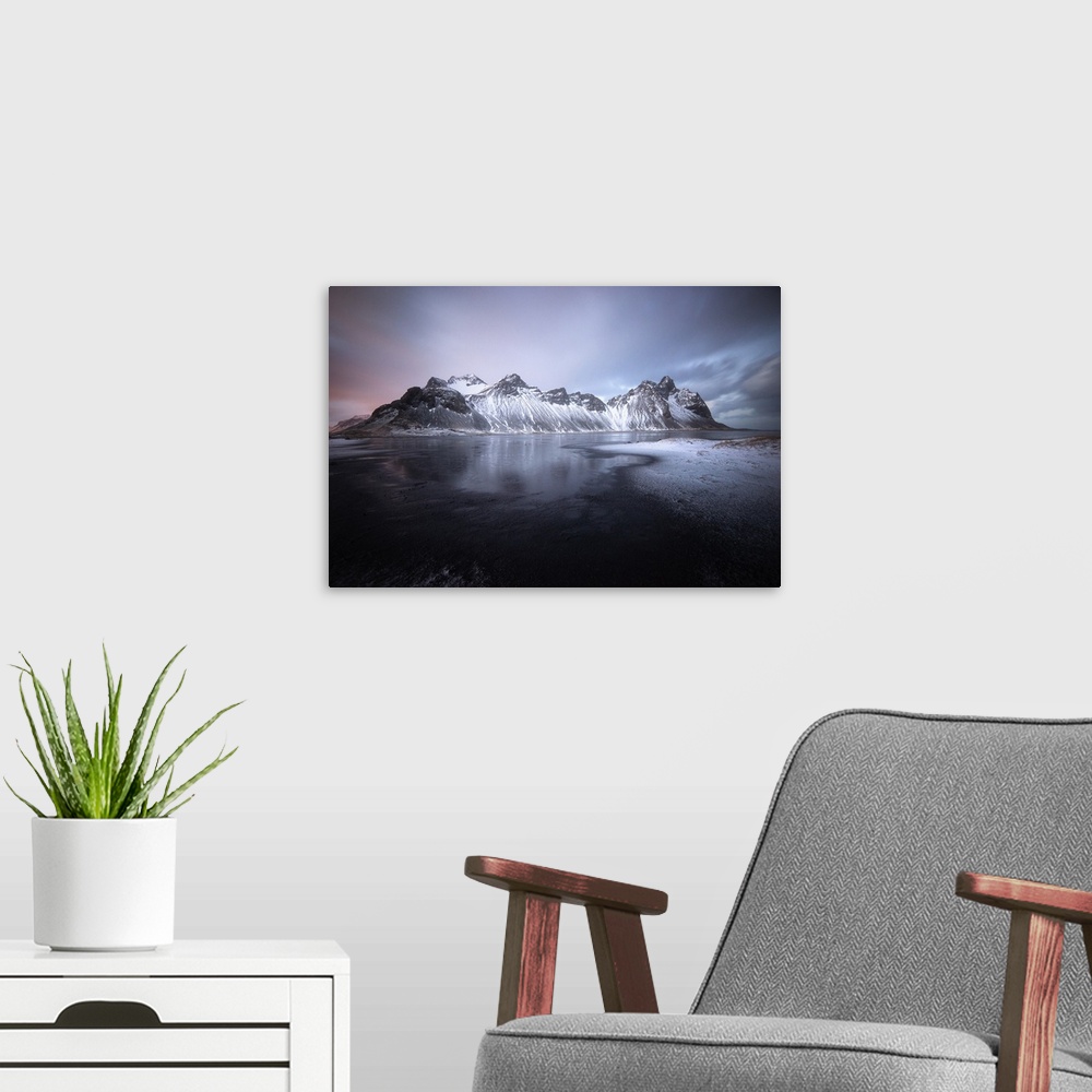 A modern room featuring Pastel sky over dark mountains covered in fresh snow in Stokksnes, Iceland.