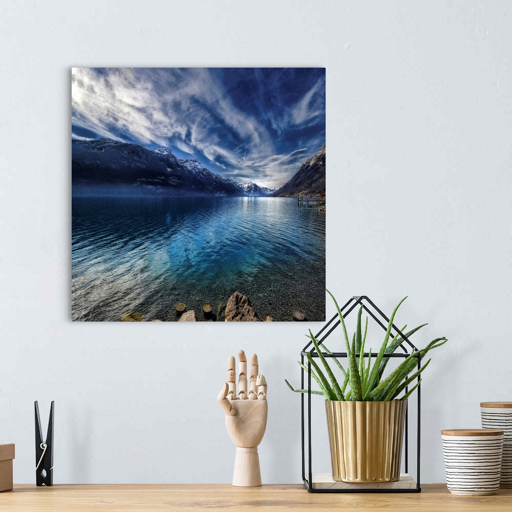 A bohemian room featuring This square shaped decorative wall art is a landscape photograph of a lake surrounded by snow cov...