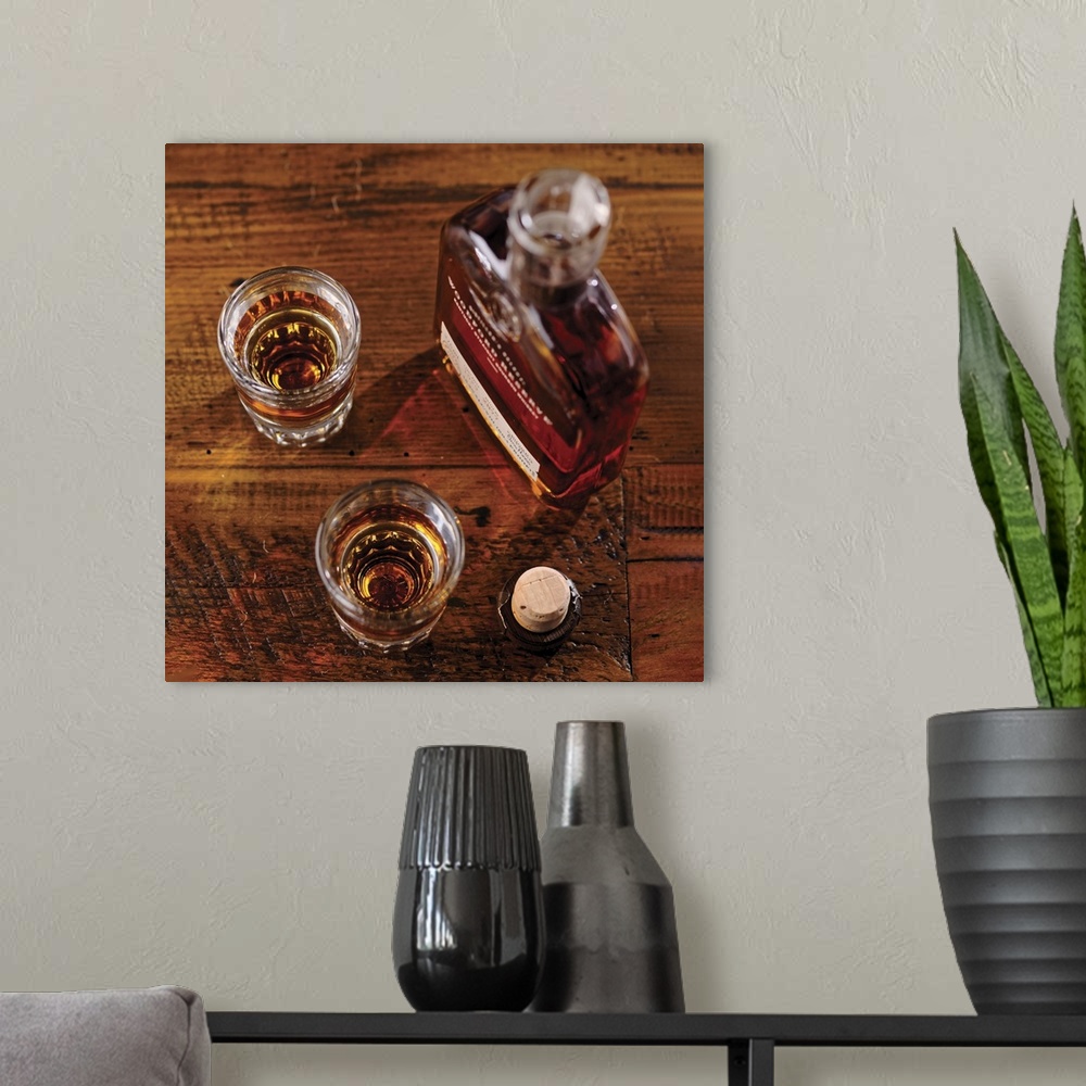 A modern room featuring Small bootle of Kentucky Strtaight Bourbon Whiskey with Shot Glasses on a Rustic Wooden Table.