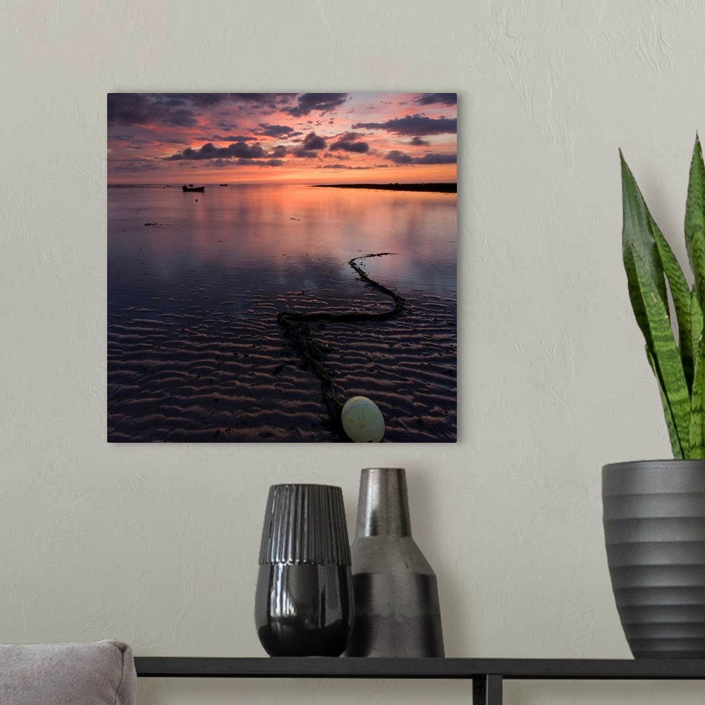 A modern room featuring A dramatic warm golden peach glowing sunrise over wet sand patterns with a bouy and chain and ref...