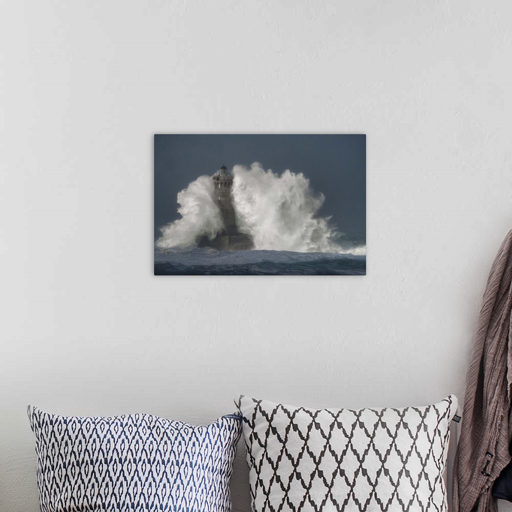 A bohemian room featuring A photograph of a lighthouse in France being hit with crashing waves.