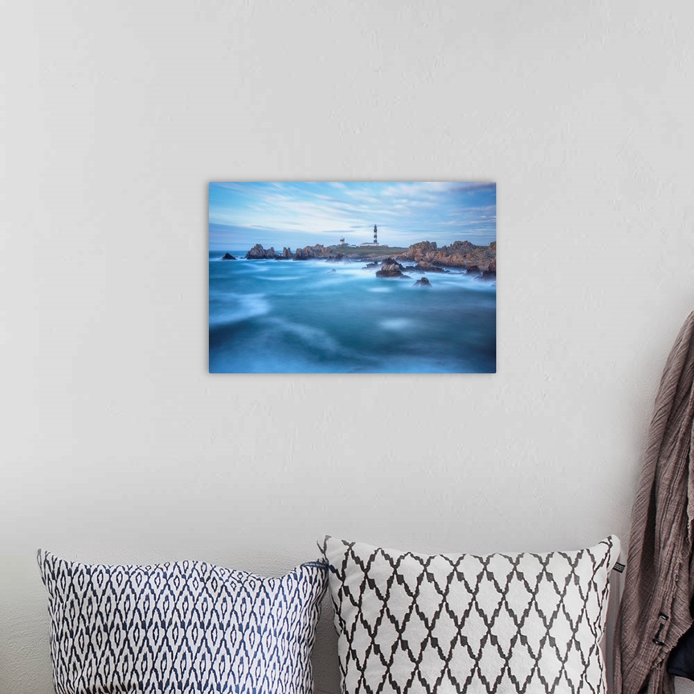 A bohemian room featuring Fine art photo of a lighthouse on a rocky coast with a cloudy sky and deep blue ocean.