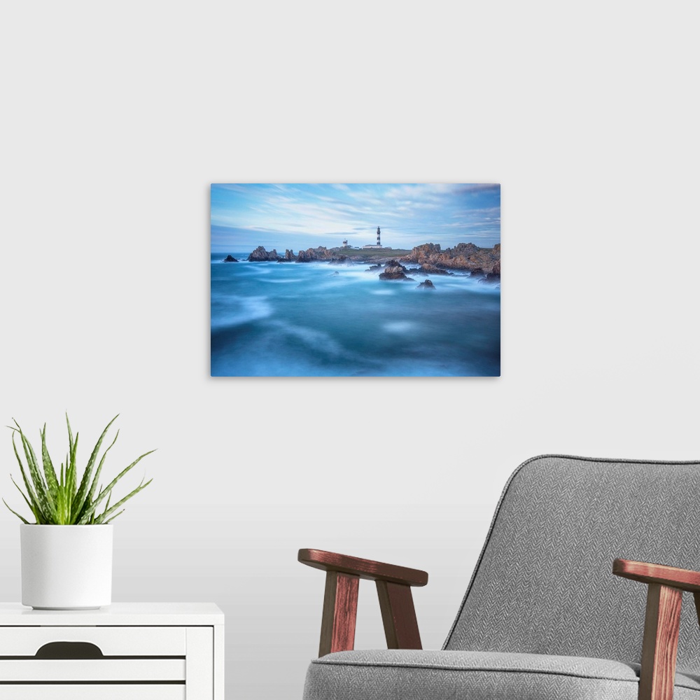 A modern room featuring Fine art photo of a lighthouse on a rocky coast with a cloudy sky and deep blue ocean.