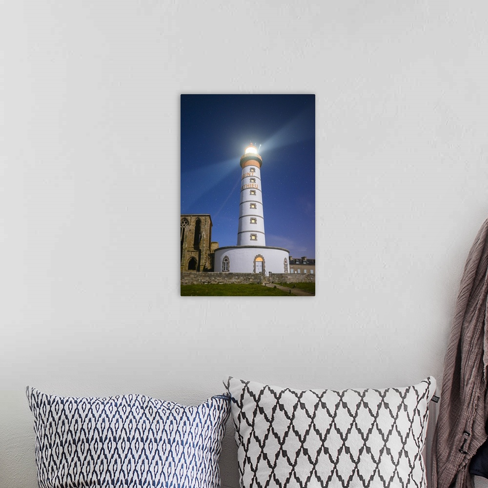 A bohemian room featuring A photograph of a lighthouse on the coast of France.