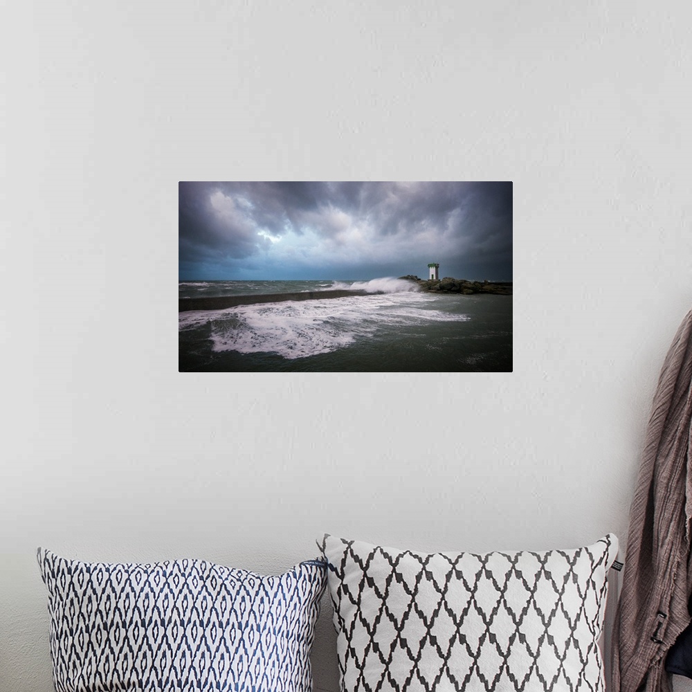 A bohemian room featuring A photograph of the French coast with a lighthouse in the distance under a sky filled with ominou...