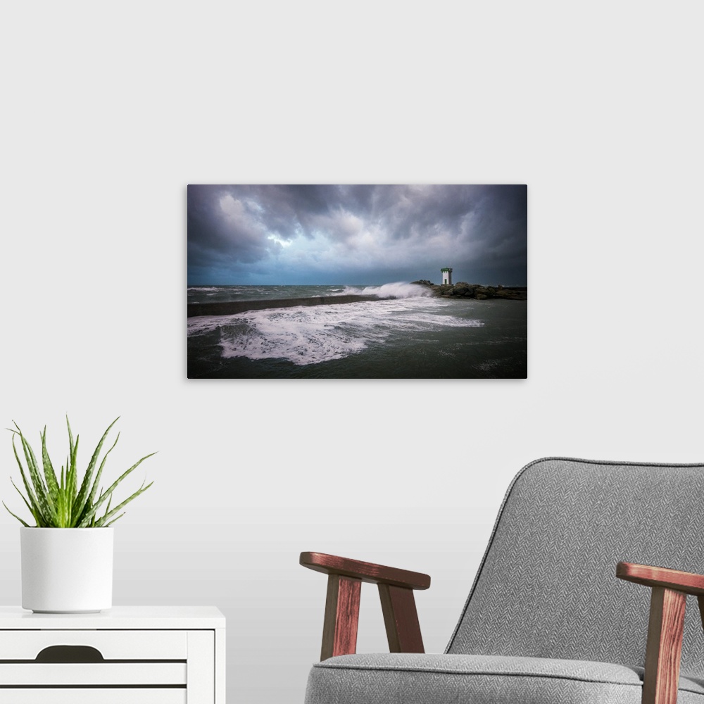 A modern room featuring A photograph of the French coast with a lighthouse in the distance under a sky filled with ominou...
