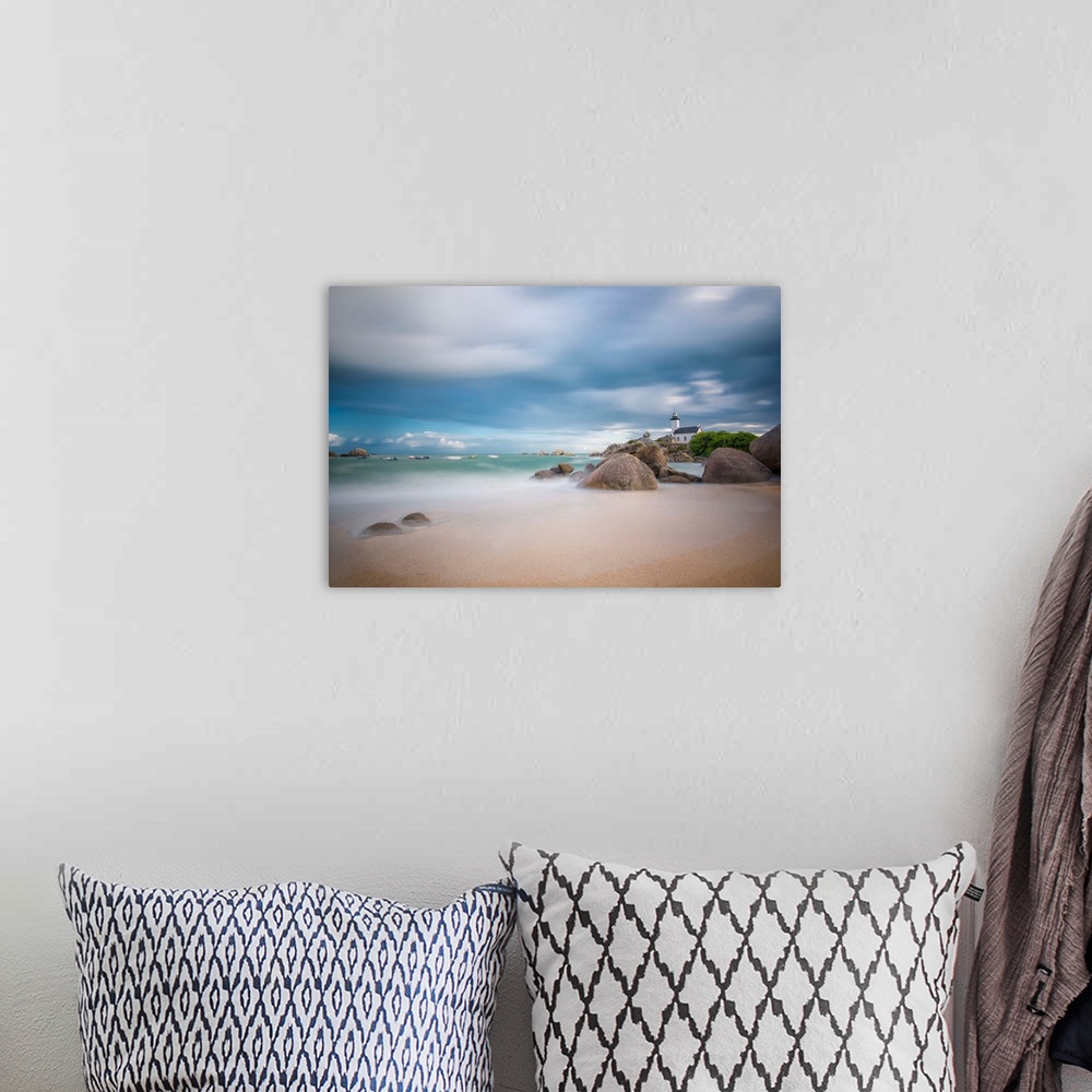A bohemian room featuring A photograph of the French coast under a blanket of soft clouds.