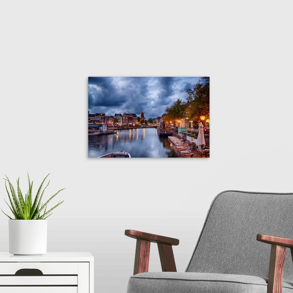A modern room featuring Canal and windmill in Leiden at night, Netherlands.