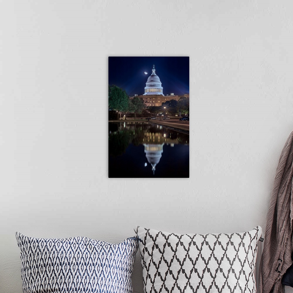 A bohemian room featuring The United States capitol building mirrored in the water below at night.