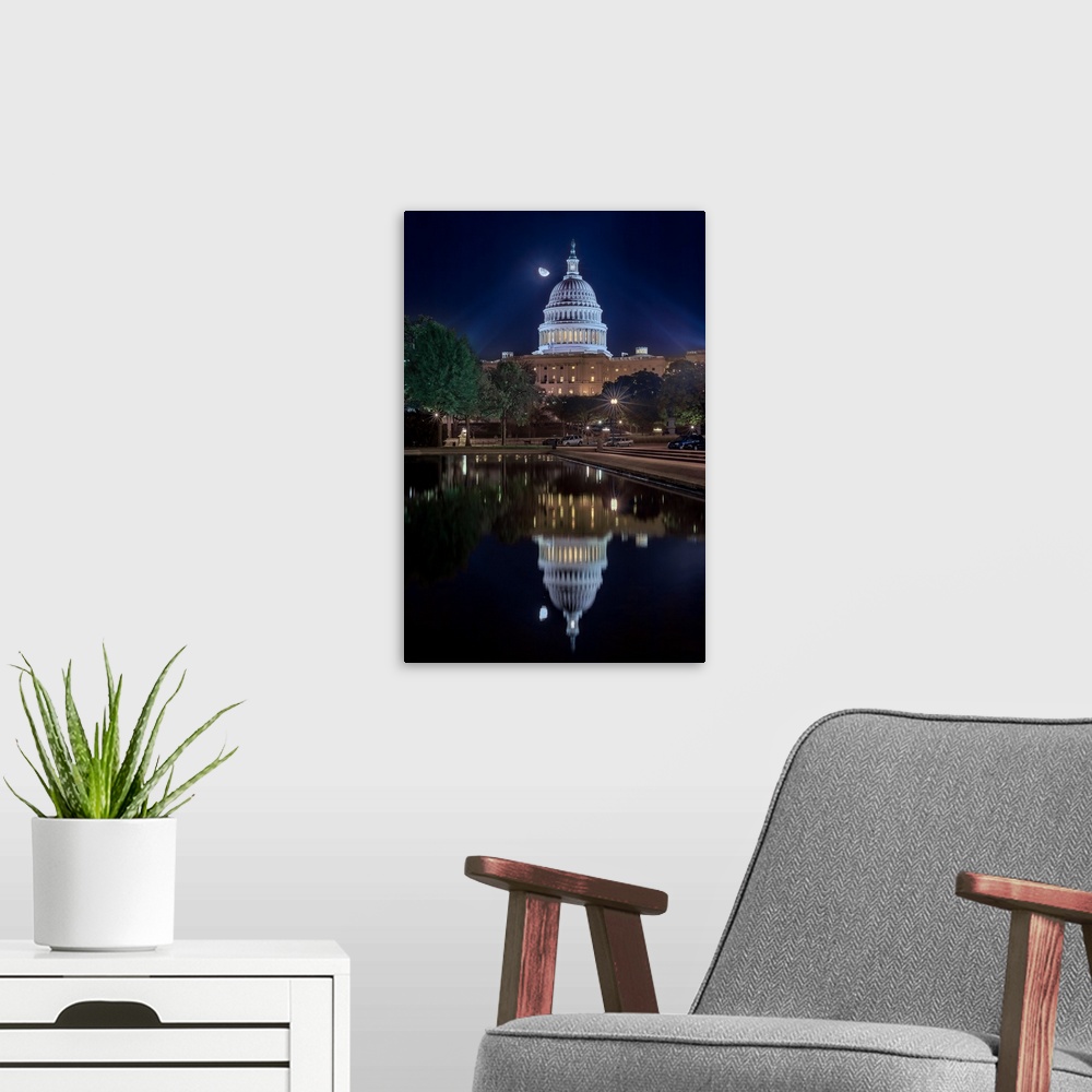 A modern room featuring The United States capitol building mirrored in the water below at night.