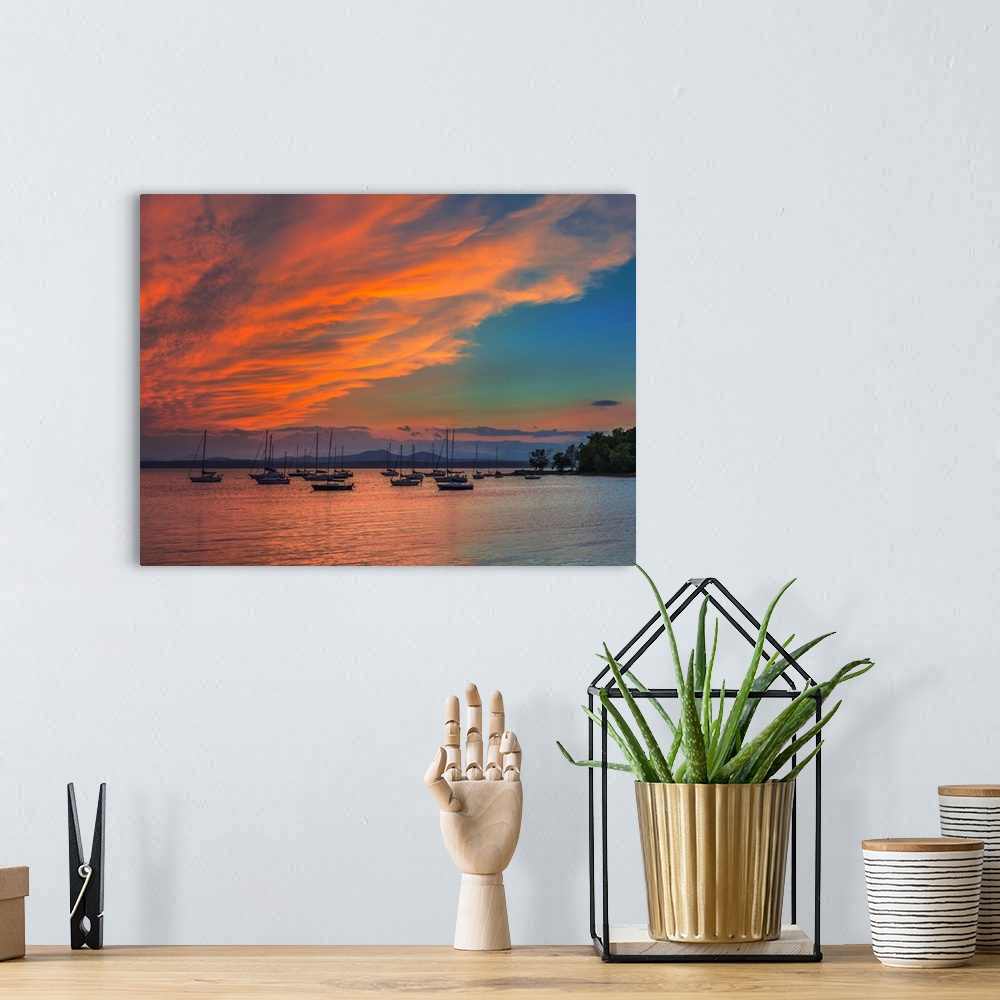 A bohemian room featuring Orange clouds glowing in the sky at sunset over sailboats in Charlotte Harbor, Florida.