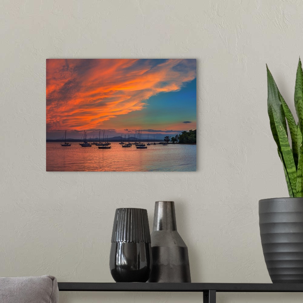 A modern room featuring Orange clouds glowing in the sky at sunset over sailboats in Charlotte Harbor, Florida.
