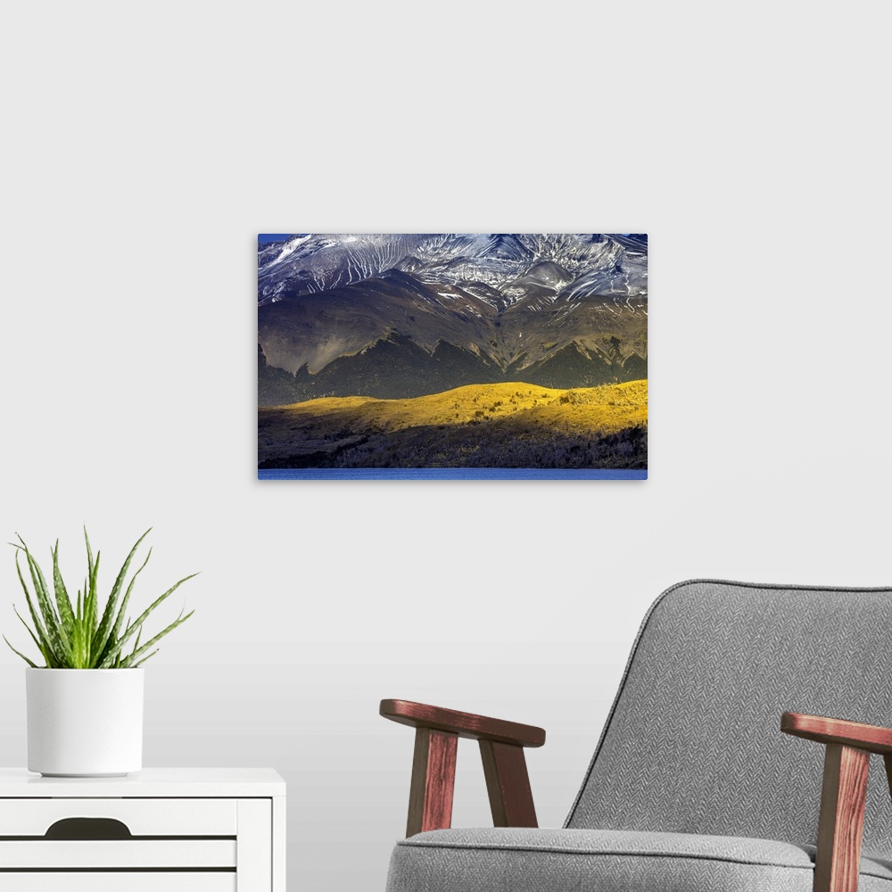 A modern room featuring Sunlight on the side of the mountains under the snowy peaks of the Andes in Chile.
